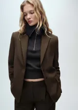 Americana color verde oliva con solapas de muesca, cierre frontal con botones, dos bolsillos con solapa, mangas largas con puños abotonados y forro interno.