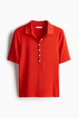 Remera polo roja de punto acanalado, corte entallado, con cuello clásico, tapeta de botones y mangas cortas.
