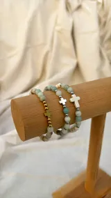 Set de pulseras elásticas con cuentas de piedra natural amazonita y separadores metálicos plateados. Incluye dijes de cruz en diferentes materiales: metal dorado, metal plateado y hueso.