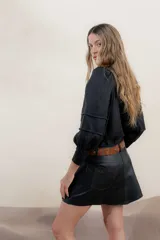 Minifalda negra de cuero con bolsillos delanteros y costuras decorativas en color ocre.