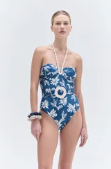 Body de lycra azul con estampado floral blanco, escote strapless, detalle de bordado en cuerda con pedrería y cinturón decorativo con hebilla circular. Incluye cuerda removible para atar al cuello y forro interior.