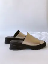 Sandalias doradas con tira para el dedo y suela track negra.