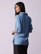 Blusa celeste en lyocell, con cuello a la base con solapa, escote en V y abertura central con botones. Manga larga regulable con presilla y botón.