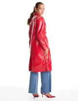 Chaqueta larga tipo trench de charol negro con acabado brillante e impermeable. Presenta cuello con solapa, cierre frontal con botones metálicos plateados y bolsillos laterales. Su diseño es de corte recto y estructura rígida.