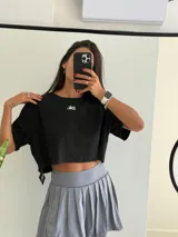 Remera negra de algodón con corte cropped y mangas cortas. Presenta un pequeño logo blanco invertido en el centro del pecho.