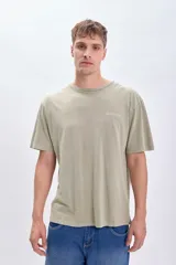 Camiseta manga corta oversize color verde con estampado de una pieza de rompecabezas con una flor en su interior y la palabra 'Island' debajo.