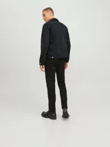 Chaqueta de denim negra con cuello clásico, cierre frontal con botones metálicos plateados, bolsillos con solapa abotonada en el pecho y mangas largas con puños abotonados.