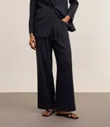 Pantalón de vestir azul marino, de corte wide leg, con cintura alta, bolsillos laterales y traseros. Se ajusta a la cintura con cinturón de cuero marrón.