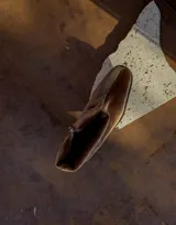 Bota de caña baja color marrón de terciopelo con efecto abullonado y cadena desmontable con el logo de la marca.