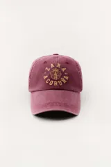 Gorra color borgoña con bordado dorado de la marca Zara, con la inscripción "Zara" y "A Coruña 1975".