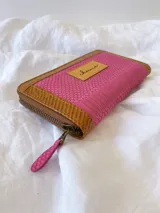 Billetera de cuero fucsia y marrón con cierre metálico y monedero interno.