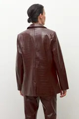Blazer de corte recto, color marrón oscuro, con textura de eco cuero de cocodrilo. Presenta solapas de muesca, un solo botón frontal y bolsillos de ojal.