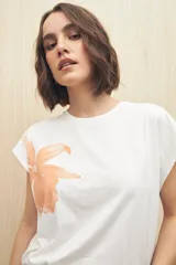 Remera blanca de manga corta con estampado de una flor color durazno en el frente.