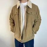 Chaqueta de pana color beige con cuello y forro de corderito blanco, cierre con botones y bolsillos con solapa en el pecho.