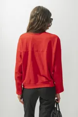 Buzo rojo de corte holgado con cuello redondo y mangas largas. Presenta una costura horizontal en el pecho y bordado con el nombre de la marca.