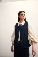 Chaleco de jean celeste con efecto lavado, sin mangas, con cuello redondo y cierre frontal con botones.