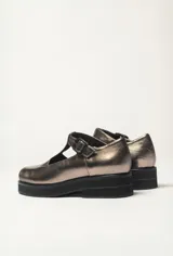 Zapato guillermina color bronce con acabado charol, suela de goma negra y plataforma.