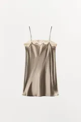 Vestido corto tipo lencero confeccionado en mezcla de seda color gris topo. Presenta escote recto, tirantes finos y detalle de encaje color crema en el escote.