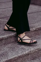 Sandalias chatitas color beige con tiras cruzadas y pulsera al tobillo, decoradas con tachas doradas.