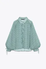 Camisa de manga larga con estampado floral en tonos verde y azul. Tiene cuello solapa, cierre frontal con botones y lazadas en los puños.