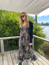 Vestido largo de tirantes con estampado de hojas en tonos marrones y celestes sobre fondo negro.