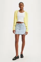 Falda corta de denim color celeste claro, con cierre frontal de botones y talle medio. Presenta un diseño asimétrico con un corte en el ruedo lateral.