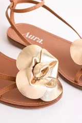 Sandalias bajas de cuero color suela, con tiras finas y aplique de flor roja en el empeine.