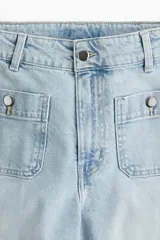 Pantalón de jean celeste de tiro alto, corte ancho, largo tobillero y bolsillos frontales con botón.
