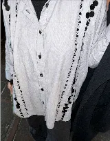 Camisa celeste a rayas verticales con bordado de mostacillas negras en los alforzas. De corte oversized y manga larga.