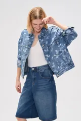 Campera de jean azul con estampado floral blanco, corte holgado, cuello camisero, cierre frontal con botones y bolsillos delanteros.