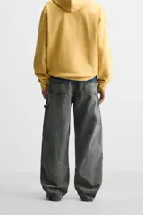 Pantalón color marrón con efecto lavado, corte relaxed fit, cinco bolsillos, aplicación de tira y bolsillo multifunción en perneras, cierre frontal con cremallera y botón.