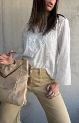 Blusa blanca de algodón con bordado broderie, escote en V y mangas largas.