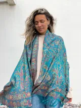 Chal o pañuelo grande de color celeste con estampado de arabescos en tonos naranja, amarillo y violeta.