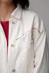 Vaquero color crudo con detalles de piedras de colores en los bolsillos, de corte ajustado.