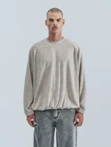 Sweater beige de corte holgado, cuello redondo y mangas largas con puños elásticos.