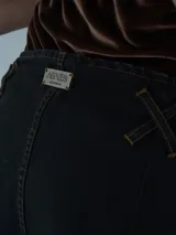 Pantalón vaquero de corte ancho, color crudo, con cintura alta y detalle de costuras cruzadas en la parte superior.