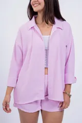 Camisa negra de corte amplio, con cuello clásico, cierre frontal con botones, manga larga con puños arremangados y bolsillo de parche en el pecho.