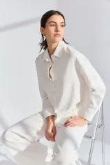 Conjunto de pijama blanco de lino y viscosa, compuesto por un corpiño de encaje, una camisa de mangas largas y un pantalón capri con lazo en la cintura.