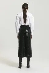 Pollera midi negra de lentejuelas con frunce en el centro delantero. El ruedo es asimétrico, más largo en los laterales que en el centro delantero, y recto en la espalda.