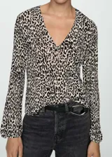 Blusa de tejido fluido color crema con estampado animal print negro, cuello en V y mangas largas abullonadas.