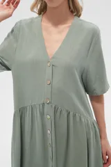 Vestido corto color crema, de corte holgado, con cuello en V y botones frontales.