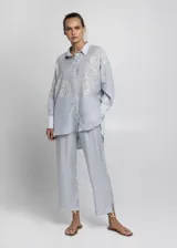 Camisa celeste de corte recto con bordados blancos.