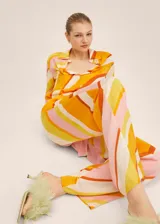 Pantalón de poliéster con estampado de rayas diagonales en tonos naranja, amarillo, rosa y blanco. Incluye cinturón de la misma tela.