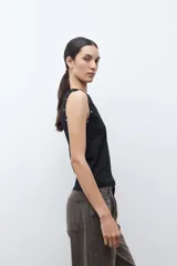 Top sin mangas color verde oliva, con cuello redondo y ojalillos metálicos decorativos a lo largo de la sisa.