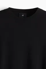 Remera negra de punto fino, con cuello redondo y mangas cortas. Corte ajustado.