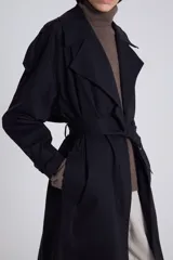 Trench negro de diseño clásico, con cinturón y silueta ajustable.