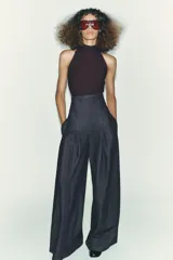 Top negro de cuello halter con cierre de botones en la parte trasera del cuello y espalda descubierta.