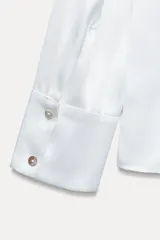 Camisa color borgoña de satén con cuello solapa, escote en pico, manga larga y cierre frontal con botones.