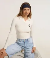 Blusa de manga larga color crema, con cuello polo, escote en V y bordado de ancla en el pecho.