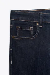 Pantalón de jean azul oscuro, de tiro bajo, corte slim fit y bootcut. Con cinco bolsillos y cierre frontal con cremallera y botón.